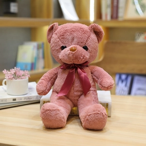 Lindo oso de peluche rosa con lazo de cinta roja sentado en un escritorio decorativo