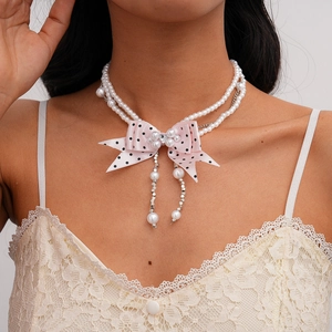 Detail view of double-layer faux pearl necklace with pink polka dot ribbon bow ornament