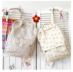Detail of floral canvas backpacks featuring a front zipper pocket and top handles