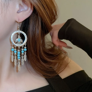 Detail of bohemian silver clip-on earrings with blue beads and feather tassels