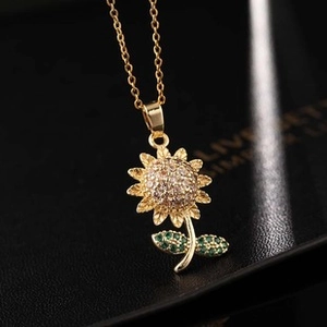 Macro shot of gold sunflower pendant with white and green zircons on a black background