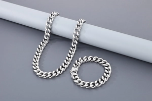 Polished silver curb chain necklace and bracelet set displayed on a grey stand