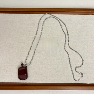 Macro view of a dark red perfume bottle pendant on a silver-tone metal beaded chain