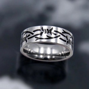 Macro shot of silver titanium steel ring with black barbed wire pattern and punk style