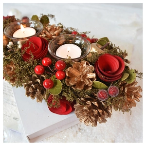 Close-up of vintage Christmas candle holder with red roses, pine cones and glass cup