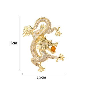 Golden dragon brooch with zircon inlay and orange bead, measuring 5cm by 3.5cm
