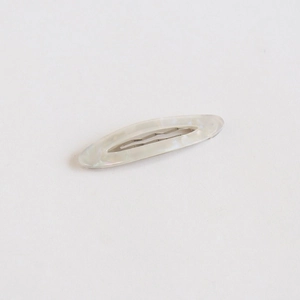 Détail d'une barrette ovale en acétate avec texture nacrée blanche et base en métal argent