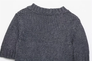 Detail of dark grey thick knit crewneck sweater showing stitching and ribbed texture