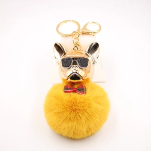 Dettaglio ciondolo bulldog dorato con occhiali da sole e pompon giallo per borsa