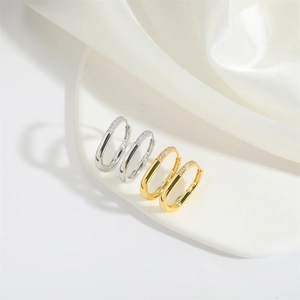Exotic U-shaped gold and silver earrings with pavé crystals on a silk background