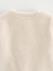 Gros plan détaillé du col d'une veste en fausse fourrure crème et du tissu pelucheux