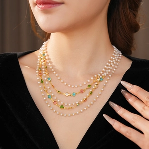 Macro detail of multi-layered pearl necklace with colorful gemstones in gold setting