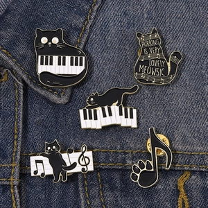 Detail of 5-piece black cat and music theme enamel pins set on blue denim jacket fabric