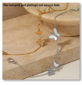 Detailed macro of gold and silver butterfly pendants with pave zircons and marble backdrop