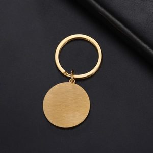 Close-up of golden stainless steel keychain with brushed round pendant on black background
