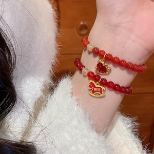 Détail macro du bracelet en perles d'agate rouge avec breloque cheval émaillé or