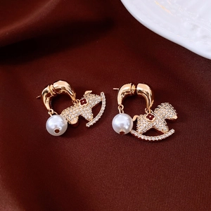Détail de boucles d'oreilles cheval plaquées or 18 carats avec cristaux et perles élégantes
