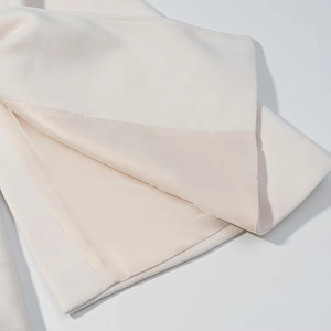 Detail shot of beige wool coat hem showing smooth inner lining and premium stitching