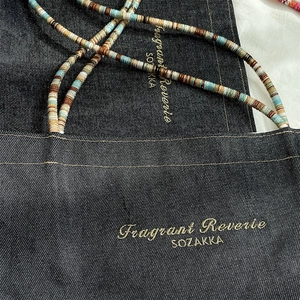 Detail of vintage denim tote bag with colorful beaded straps and gold embroidery