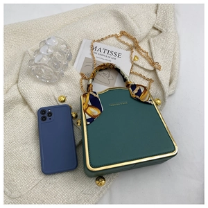 Close-up of green structured mini box bag with gold metal trim and silk scarf handle detail