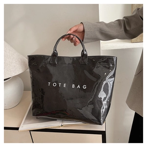 Close-up of a glossy black tote bag with white TOTE BAG lettering in a modern setting