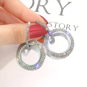 Elegant silver circle earrings with paved rhinestones held by a model for a stylish look
