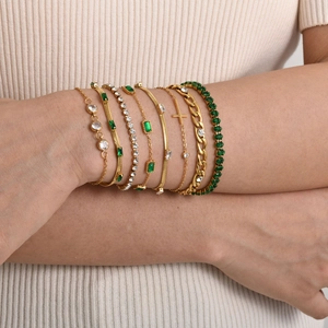 Elegant gold stacked bracelets with emerald green stones and a cross pendant for women