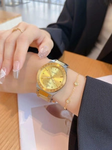 Macro shot of stylish gold and silver steel watch paired with jewelry on a wrist