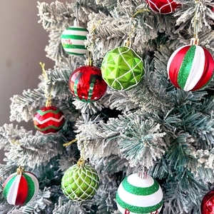 Detail of red and green striped Christmas ball ornaments hanging on a snowy tree