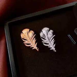 Exquisite 18k gold and silver feather brooches with pavé zircon in a luxury jewelry box