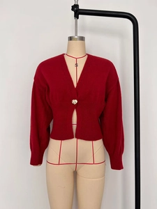 Detail of red V-neck knit cardigan with unique gold petal button and ribbed waist