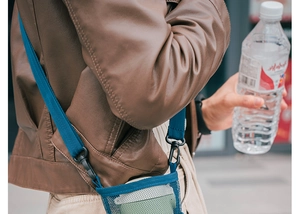 Blue mesh water bottle carrier bag with adjustable strap worn cross-body in daily use