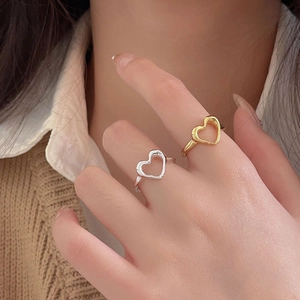 Close-up of gold and silver heart-shaped hollow rings worn on hand for elegant detail