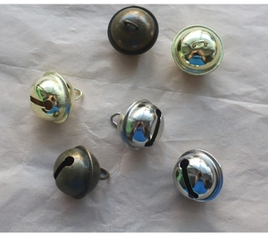 Gros plan de clochettes de 22mm en bronze or et argent sur fond de papier texturé