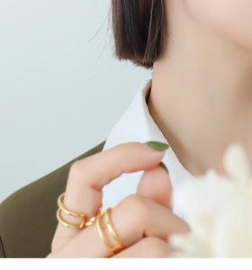 Close-up of 18k gold plated hollow geometric rings and H-link band worn by a model