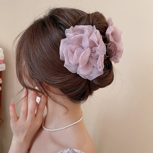Detail einer hellrosa Haarklammer mit Organza-Blume für eine braune Hochsteckfrisur