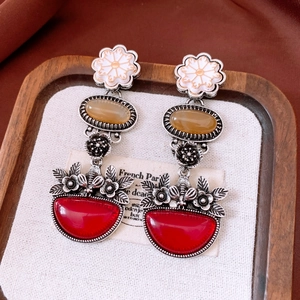 Macro shot of vintage floral earrings with red and amber stones on display tray