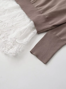 Detailed close-up of ribbed cuffs and delicate lace stitching on a V-neck knit top