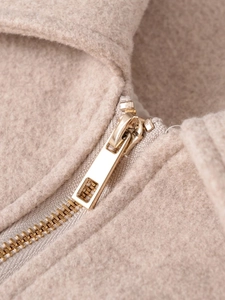 Detail of soft beige fleece fabric and high-quality gold metal zipper on casual jacket