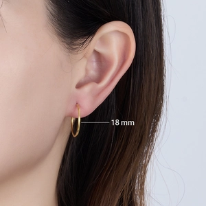 Close-up of 18mm golden sterling silver hoop earrings worn on ear for minimalist style