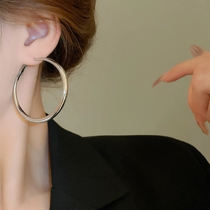Close-up of polished silver hoop earrings on model with high gloss mirror finish