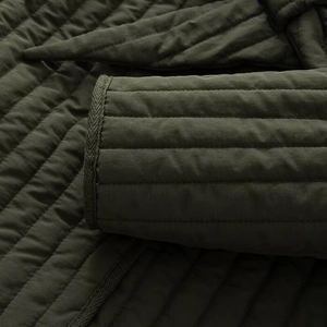Close-up of army green quilted jacket with detailed stitching and ribbed cuffs
