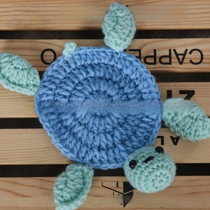 Macro shot of handmade crochet turtle coaster in blue and green knitted yarn texture