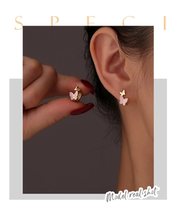 Detail view of pink butterfly earrings in gold finish worn by a model for elegant look