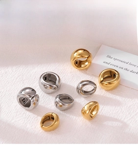 Detailed view of polished gold and silver hoop earrings on a textured fabric background