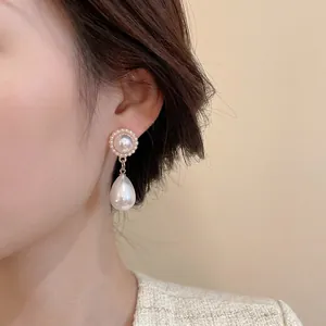 Eleganti orecchini a goccia dorati con perle tonde e a goccia su una modella