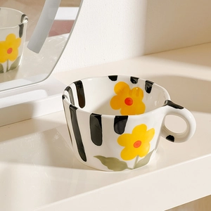 Detailed view of hand-painted ceramic mug with black stripes and yellow flowers
