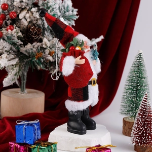 Detailed plush Santa Claus standing with red plaid hat and gift bag in a festive setting