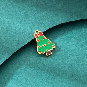 Close-up of green enamel Christmas tree pendant with golden base and red bow detail