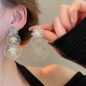 Vue macro de boucles d'oreilles pendantes argentées à trois cercles évidés avec texture